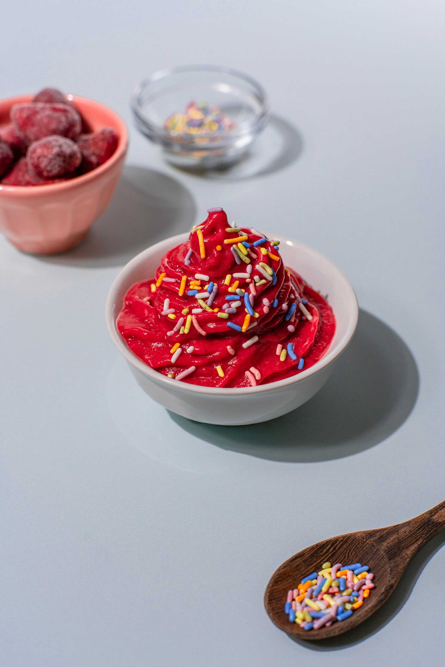 A bowl of strawberry soft serve with rainbow sprinkles sits at the center of the image.